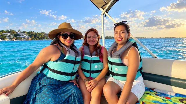 Tres viajeras con chalecos sentadas a bordo de un pontón.