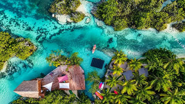 Aerial view of Los Rapidos in Bacalar, with turquoise water, vegetation and a terrace beside the channel.